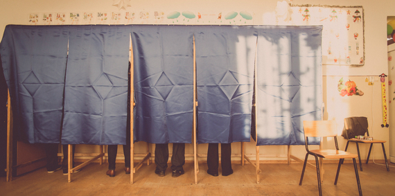 A group of people standing in front of voting booths.