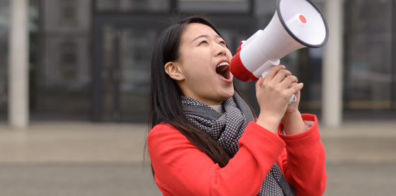 A woman holding a megaphone up to her mouth.