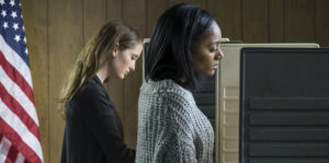 Two women standing next to each other in front of a computer.