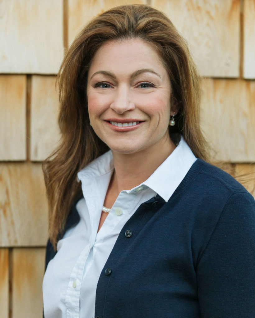 A woman standing in front of a wooden wall.