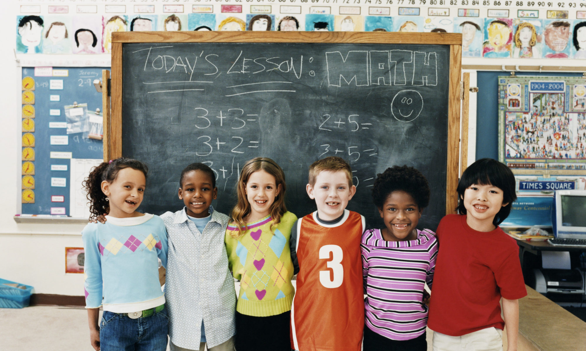 A group of children standing in front of a chalkboard.