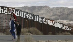 A man and woman standing in front of the border fence.