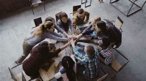 A group of people sitting around each other with their hands in the middle.