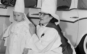 An old black and white photo of a woman dressed in a white robe with a child.